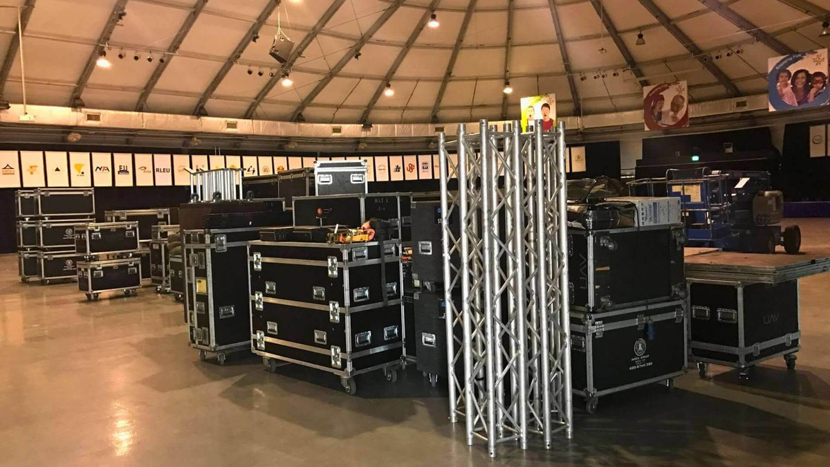 Flight cases and truss sections staged on a venue floor before rigging.
